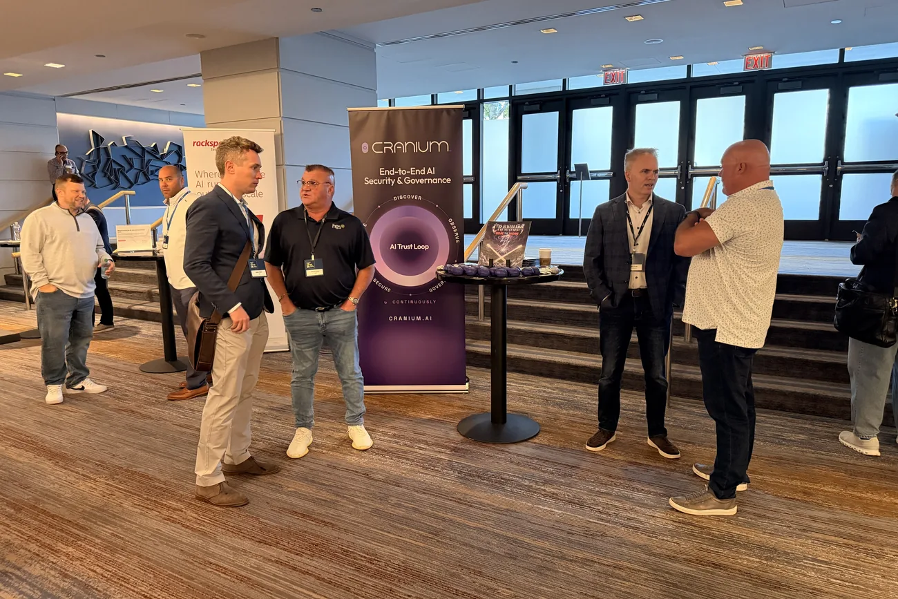 Cranium team members in conversation with HGS Build for the Future attendees beside the Cranium AI Trust Loop banner in Chicago