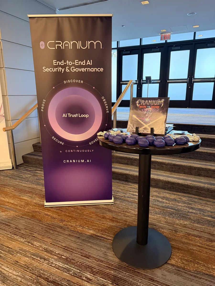 The Cranium &lsquo;End-to-End AI Security & Governance&rsquo; banner and AI Trust Loop next to a high-top with the Secure the Machine vinyl